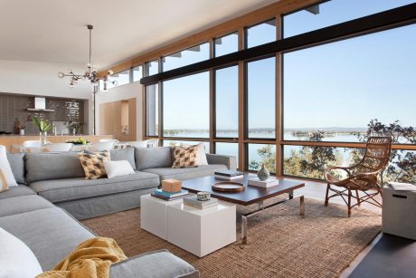 Spacious open-concept living room with floor-to-ceiling windows, modern furniture, and scenic view.
