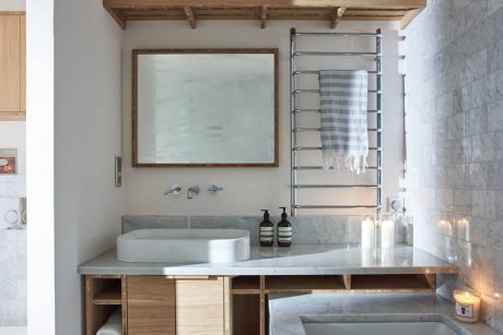 Rustic wooden beams, marble vanity, sleek faucet, and modern towel rack in bathroom.