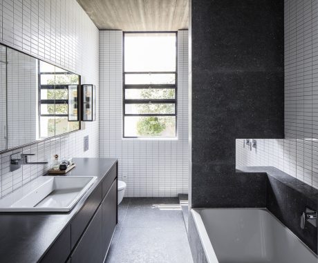 Sleek, modern bathroom with floor-to-ceiling windows, black stone accents, and tiled walls.