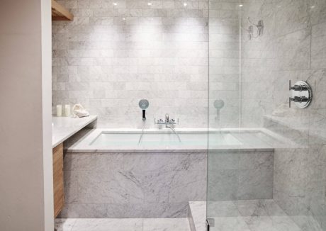 Luxurious bathroom with marble tile walls, glass shower, and modern fixtures.