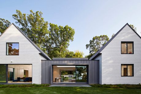 Modern farmhouse-style home with clean lines, large windows, and a central glass-enclosed entryway.