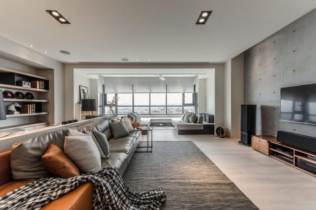 Spacious living room with floor-to-ceiling windows, modern furniture, and open shelving.