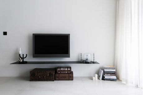 A minimalist living room setup with a TV, vintage trunks, and a collection of books.