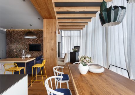 Warm wooden beams, herringbone tile wall, minimalist dining space with pops of color.