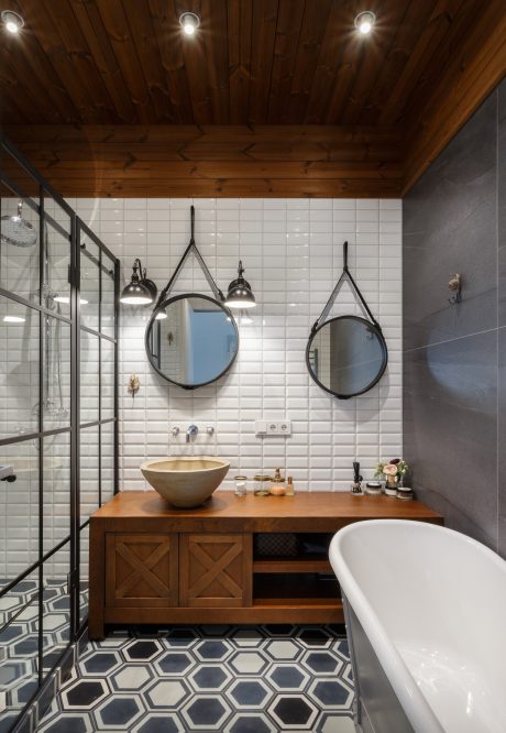 Rustic bathroom with modern hexagonal tile floor, double vanity, and overhead lighting.