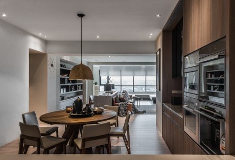 Modern open-concept living space with wood dining table, pendant light, and built-in cabinetry.