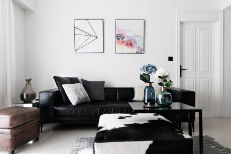 Sleek, modern living room with minimalist wall art, black leather sofa, and patterned rug.