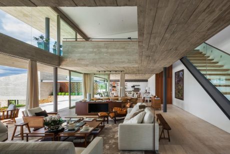 Spacious open-concept living area with concrete walls, wood ceiling, and glass walls.
