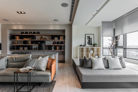 Elegant modern living space with sleek shelving, plush seating, and large windows.
