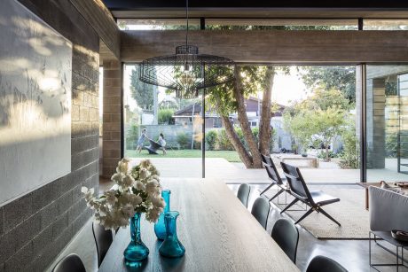 Spacious open-concept living area with large windows, modern lighting, and lush greenery.