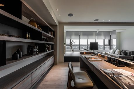 Sleek, modern kitchen and living room with floor-to-ceiling windows, dark wood cabinets.
