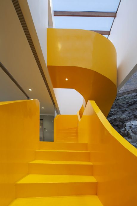 Vibrant yellow geometric staircase with natural lighting from above, creating a striking architectural design.