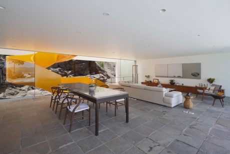 Sleek, modern living space with stone walls, yellow accents, and a large dining table.