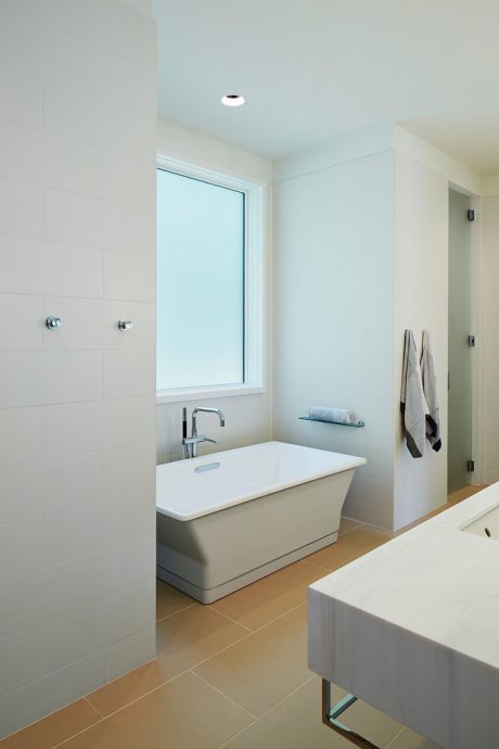 Contemporary bathroom with sleek freestanding tub, minimalist vanity, and large window.