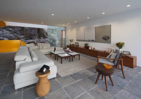 Spacious living room with natural stone walls, minimalist furnishings, and a sleek, modern design.
