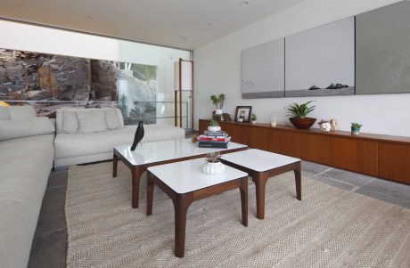 Sleek, modern living room with glass walls, stone accent, and minimalist furniture.