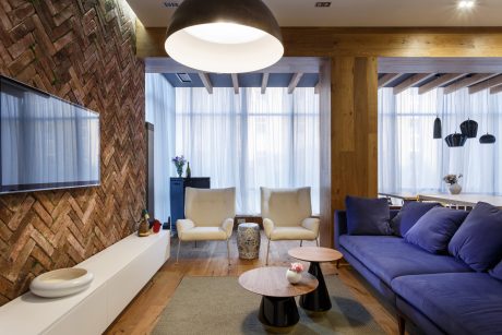 Warm, modern living room with exposed brick, wood beams, and sleek furniture.