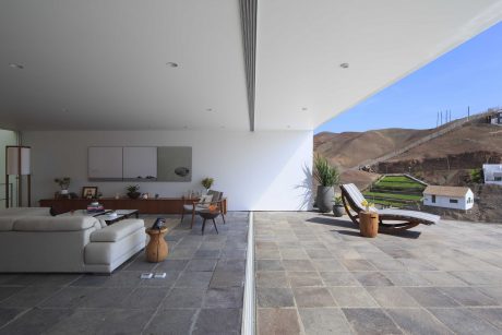 Spacious modern living area with panoramic views, sleek furnishings, and natural stonework.