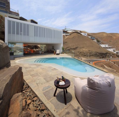 Sleek modern architecture with a stylish poolside lounge area overlooking a hillside.