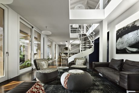 Sleek and modern interior with spiral staircase, patterned furniture, and large artwork.