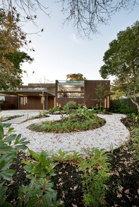 A modern home with large glass windows and natural landscaping elements.