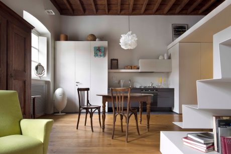 Rustic wooden beams, modern white cabinetry, and a mix of vintage and contemporary furnishings.