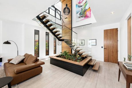 Spacious open-concept room with modern staircase, wooden accents, and indoor planter feature.
