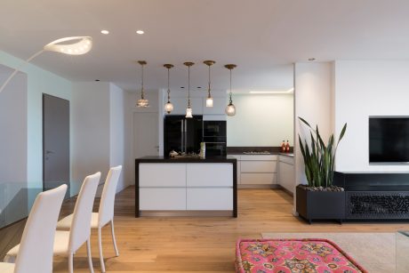Sleek kitchen with pendant lights, modern island, and wood flooring complementing the decor.