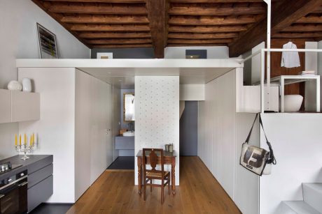 Warm wooden ceiling, minimalist furnishings, and open layout create a cozy, modern space.