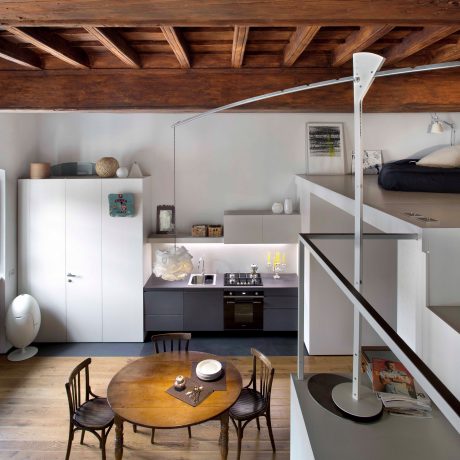 Rustic wooden beams, industrial lamps, and a modern kitchen in this cozy loft space.