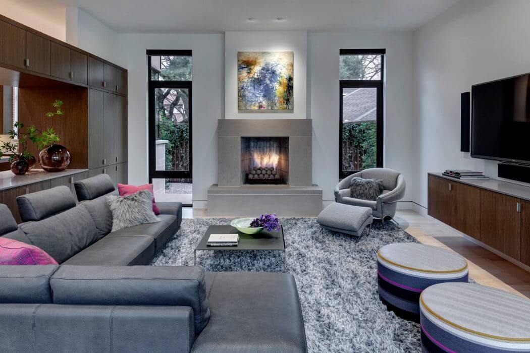 Bright, modern living room with a concrete fireplace, built-in cabinets, and large windows.