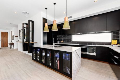 Sleek, modern kitchen with dark cabinets, marble countertops, and pendant lighting.