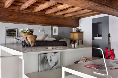 Rustic wooden beams contrast with modern gray tones and functional furniture pieces.