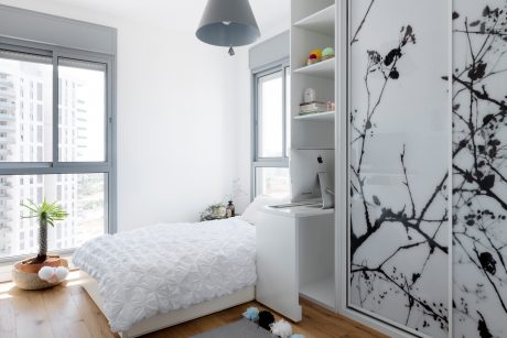 Minimalist bedroom with large window, built-in shelving, and monochrome floral artwork.