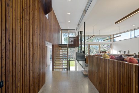 Spacious modern interior with wooden wall panels, open staircase, and cozy seating area.