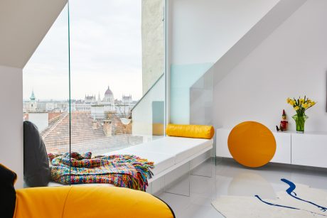Bright, modern apartment with panoramic city view, colorful bedding, and playful decor.