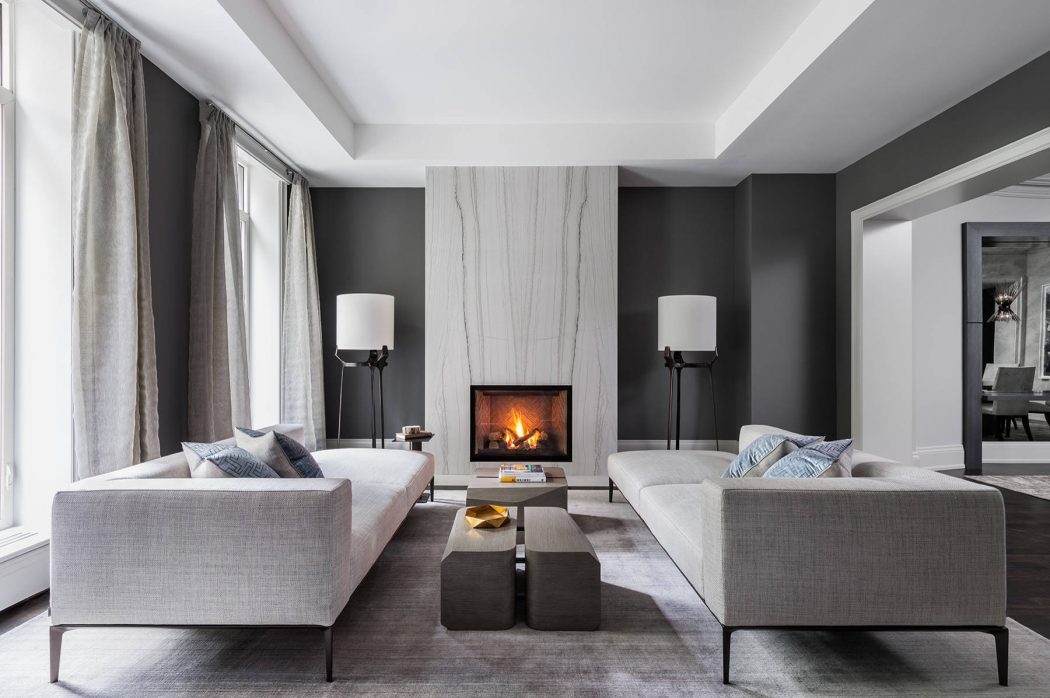 Elegant living room with sleek gray sofas, fireplace, and minimalist lighting fixtures.
