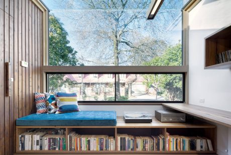 Cozy reading nook with expansive window overlooking lush outdoor scenery.