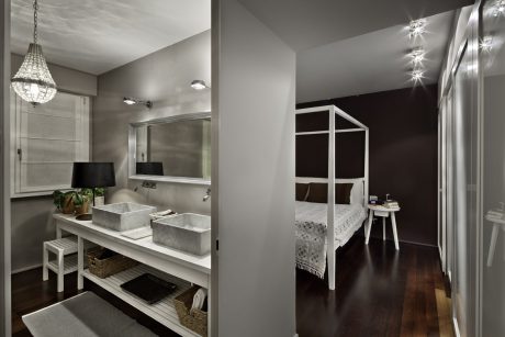 A modern bathroom with gray countertops and a bedroom with a canopy bed and dark walls.