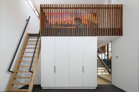A modern interior design with an elevated wooden slat wall, built-in storage cabinets, and a wooden staircase.