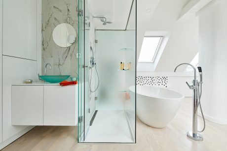 Elegant bathroom with marble-like tiles, freestanding tub, and modern fixtures.