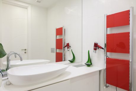 Modern, minimalist bathroom with red and white color scheme, floating vanity, and towel heater.