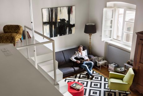 A cozy living space with modern furnishings, artwork, and a person playing guitar.