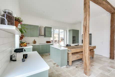 Spacious modern kitchen with sleek green cabinetry, wood accents, and ample natural light.