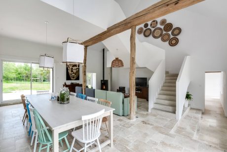 Rustic wooden beams, earthy tile flooring, and a modern dining table create a cozy ambiance.