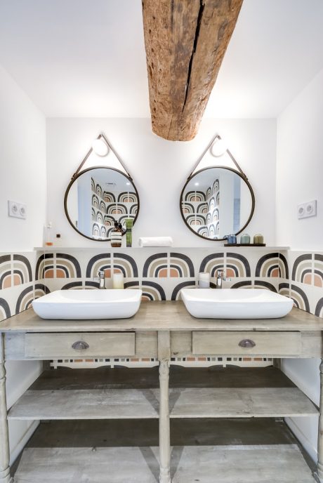 Rustic wood beam, retro-inspired wall tiles, double vanity with modern vessel sinks.