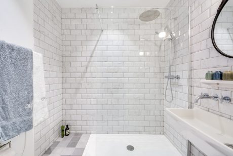 A minimalist bathroom with white subway tile walls, a tiled shower, and recessed lighting.