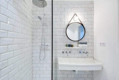 Minimalist bathroom design with subway tile walls, round mirror, and wall-mounted sink.