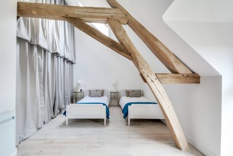 Rustic wooden beams frame a cozy bedroom with twin beds and minimalist decor.