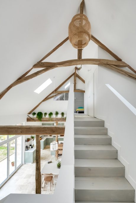 This interior features a lofted space with exposed wooden beams, a staircase, and a cozy living area.